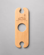 A wooden Wine Butler that holds two glasses and balances on the neck of a bottle of wine.