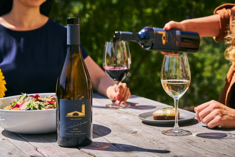 Woman pouring red wine into glass held by another person