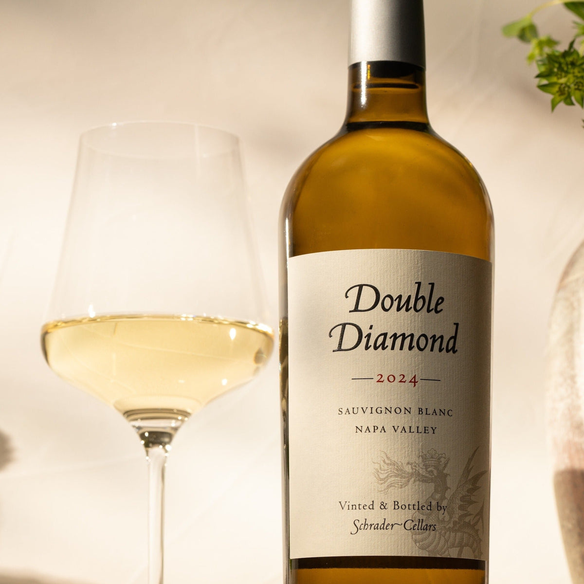 Bottle of Double Diamond 2024 Sauvignon Blanc with a glass and decorative elements on a light background