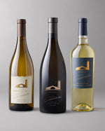 3 bottles of white wine on a grey background