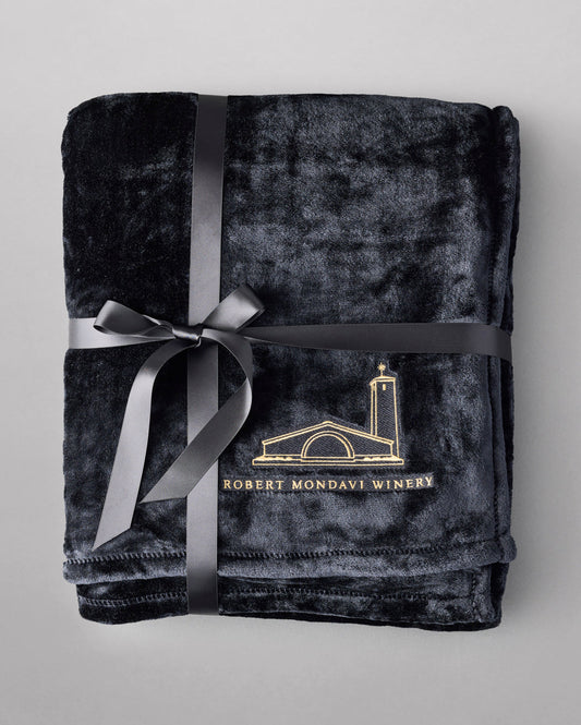 A black blanket with the Robert Mondavi Logo folded and tied with a ribbon