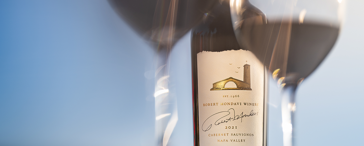 Wine bottle with a label in front of two wine glasses on a blue background