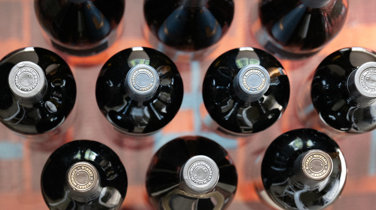 Row of black wine bottles with visible labels on a blurred background