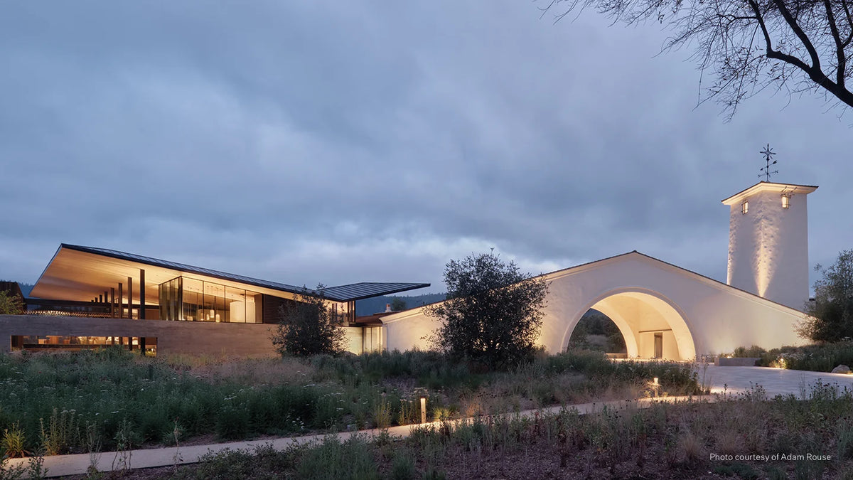 The new Robert Mondavi Winery Tasting Room on the left side, the original Arch and Tower on the right side, and native grasses and plants in the foreground